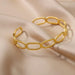 Gold open-link bracelet displayed on a beige satin fabric.