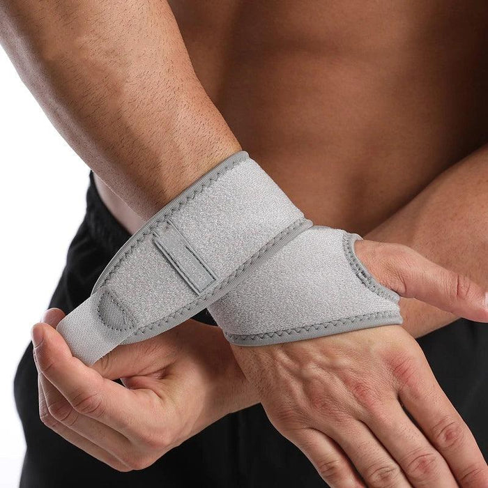 A man wearing a gray wrist support wrap. He is pulling it tight across his wrist with his other hand, showing the supportive fit of the wrap.