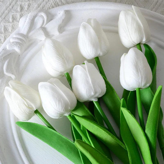 A bunch of artificial white tulips on a decorative white plate.