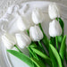 A bunch of artificial white tulips on a decorative white plate.