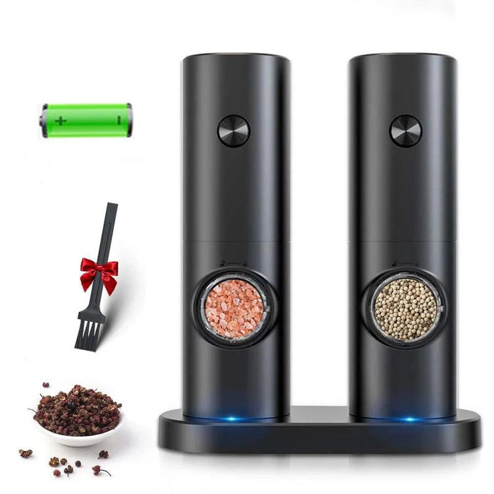 Two black electric grinders on a base with a rechargeable battery and a small brush, filled with salt and peppercorns.