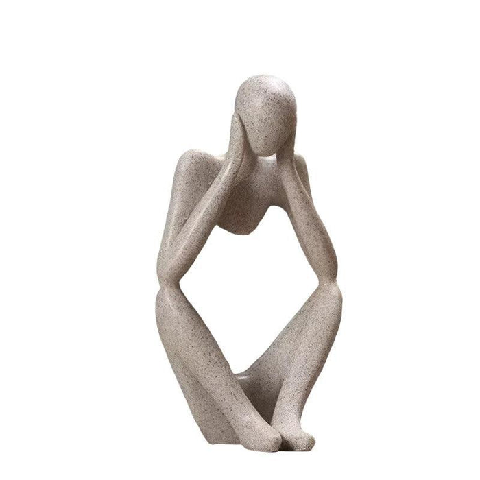 Sand color minimalist abstract sculpture of a figure sitting with hands placed on either side of the head.