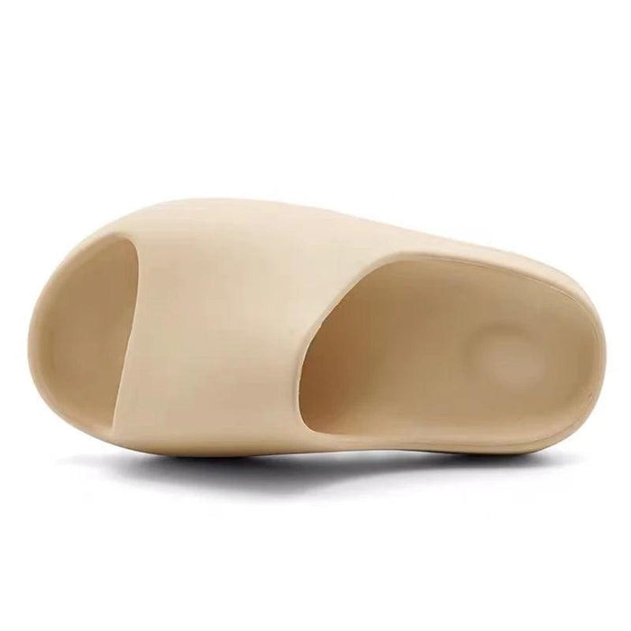 A single beige slide sandal displayed on a white background, showing its simple design and contoured footbed.