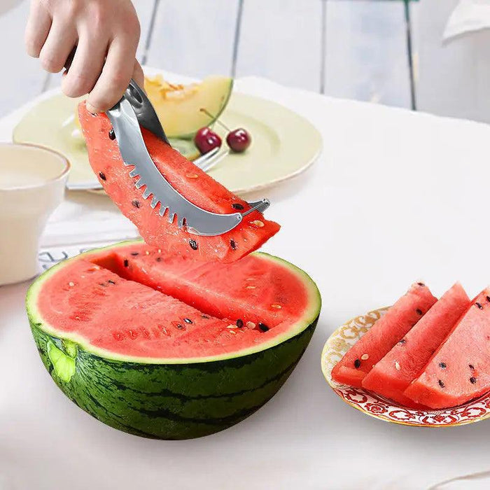 The slicer is being used to lift a slice of watermelon from a halved watermelon, demonstrating its function of both cutting and lifting the slices efficiently.