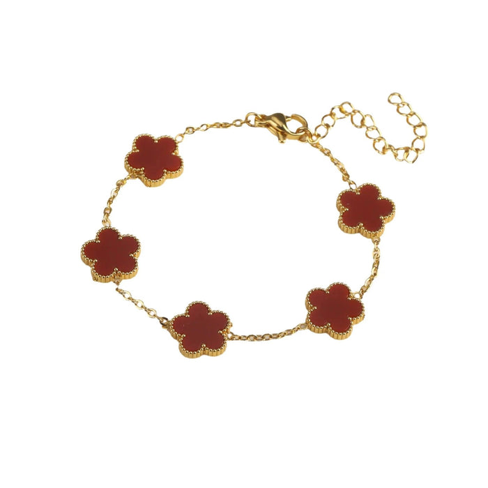 A gold bracelet, designed with a flower-shaped pendant with a red center.