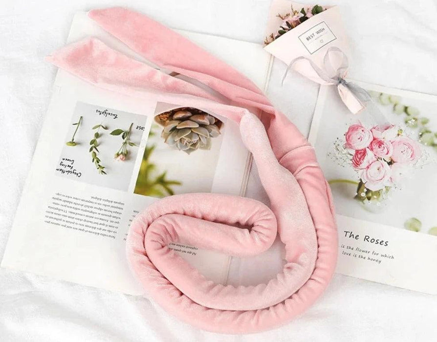 A pink, soft hair curling band displayed on an open book with flowers.