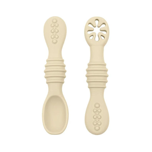 A close-up of two beige baby spoons, one with a regular spoon shape and the other with a cut-out flower design, against a white background.