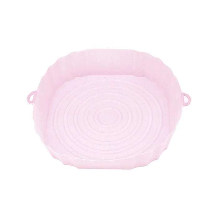 An empty pink silicone air fryer liner with a spiral design at the bottom, placed on a white background.