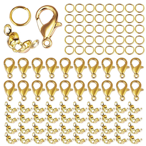 A close-up of gold-colored jewelry findings, including lobster clasps, crimp covers, and jump rings, highlighting the shiny finish and variety within the set.