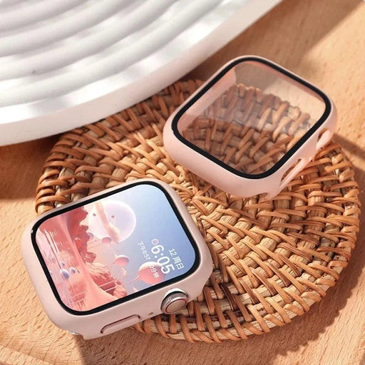 A smartwatch with a pink protective case is displayed on a woven mat, with a spare case next to it. The watch screen shows a digital display with the time and date.