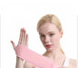 A woman with blonde hair is holding up her hand, displaying a light pink wrist support wrap that is wrapped around her wrist. The wrap is made of a soft material, and she is pulling the end of it to show its length.