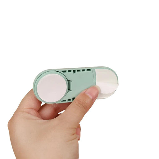 mint green child safety lock is shown being opened to reveal its adhesive back. The lock appears sturdy and easy to use, designed to be attached to surfaces to prevent children from opening cabinets or drawers.