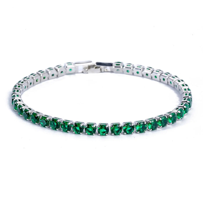 Silver tennis bracelet with green stones on a white background.