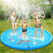 Three kids in swimsuits play on the splash mat with water spraying up in a sunny backyard.