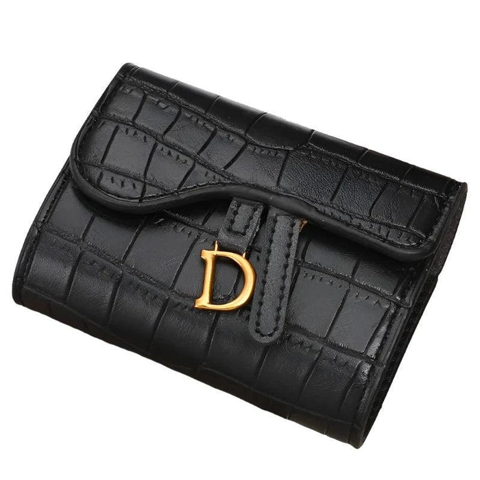 A close-up of a black crocodile-pattern wallet with a gold "D" buckle, isolated on a white background.