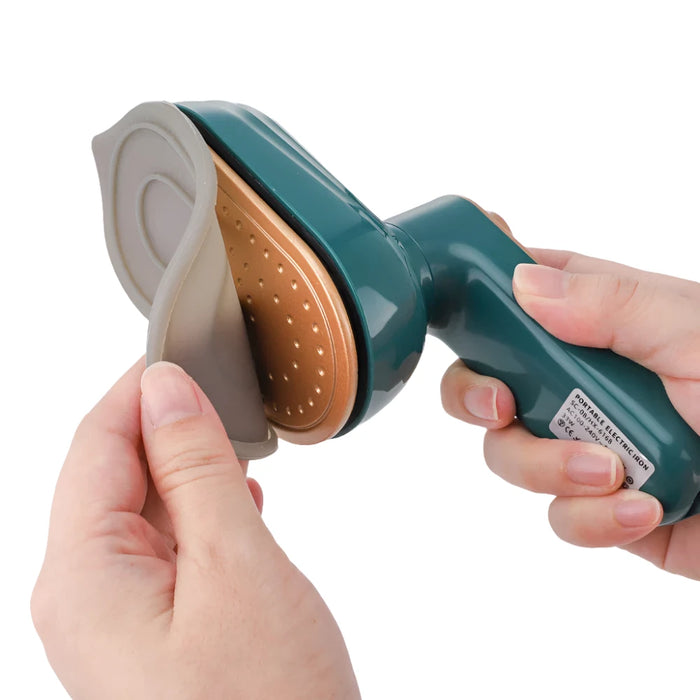 Close-up of hands peeling off a protective cover from the head of a garment steamer, revealing the heating element.