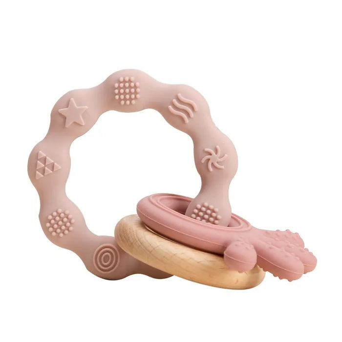 A light pink silicone teether ring with pink various textured patterns and a wooden ring attached to it.