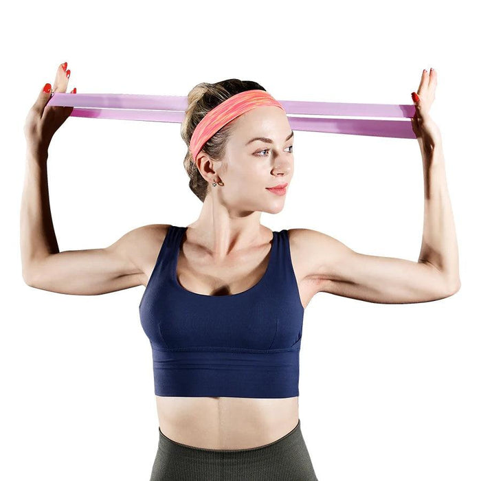 A woman using a pink resistance band, stretching it behind her head.