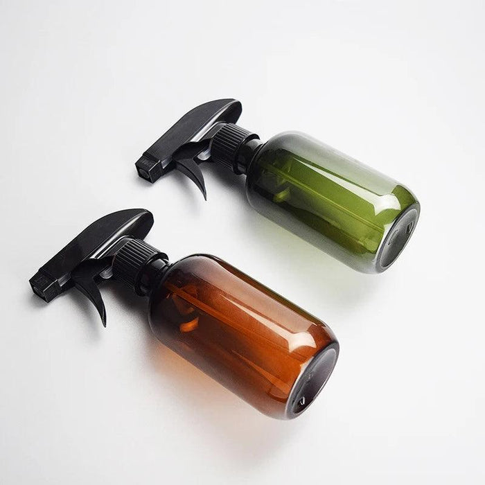 Two spray bottles, one amber and one green, with black spray heads on a white background.