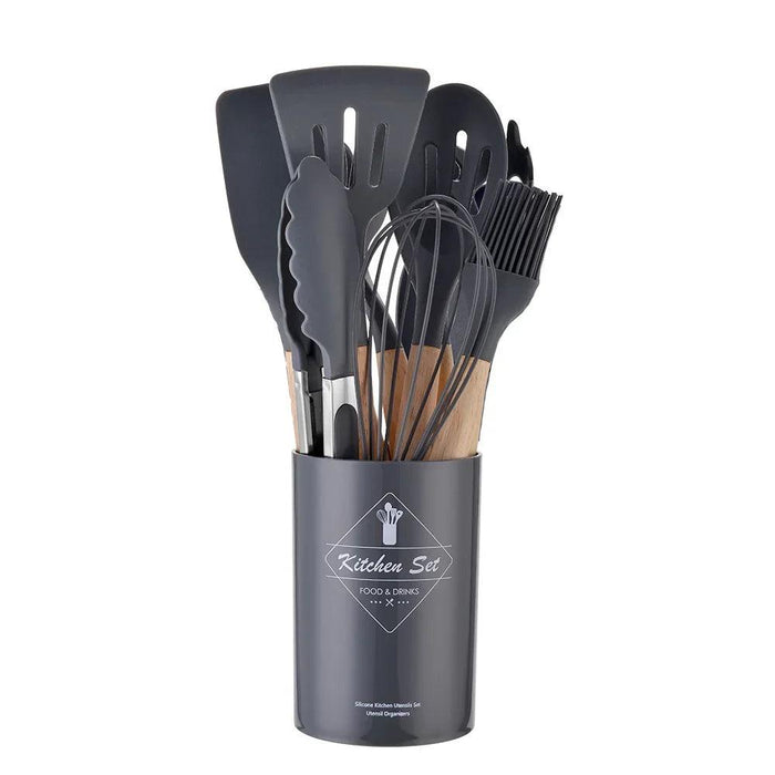 A set of black silicone kitchen utensils with wooden handles in a matching holder.