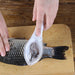 A person using the fish scaler tool to remove scales from a fish on a cutting board, with scales visible inside the tool's cover.