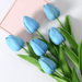 A bouquet of sky blue tulips with green leaves.