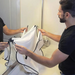 A man setting up a white beard trimming bib in front of a mirror.